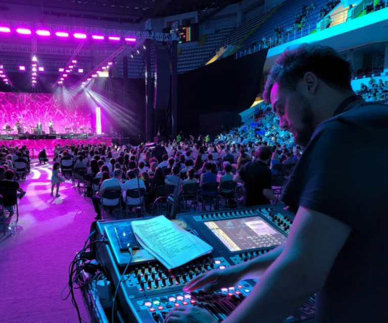 AV technician operating a lighting console at a live event