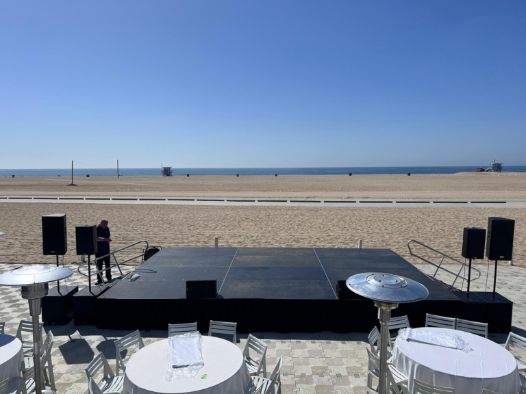 Outdoor stage deck with speakers set up on the beach for an event